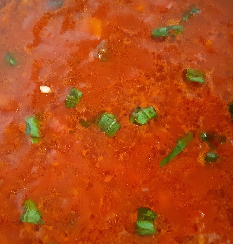 A thick red tomato sauce with green basil leaves olive oil and garlic