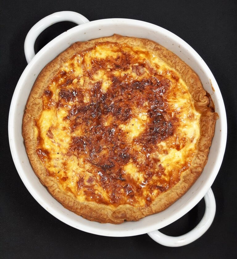 A golden color baked tart with eggs and cheese in a white pan