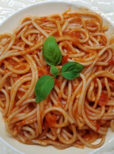 A dish with spaghetti with red tomato sauce and basil