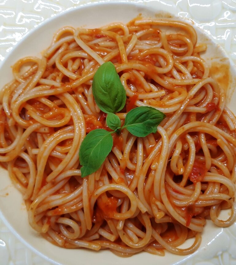 A dish with spaghetti with red tomato sauce and basil