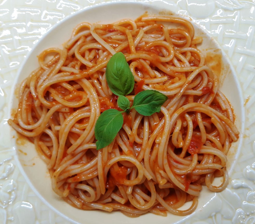 A dish with spaghetti with red tomato sauce and basil