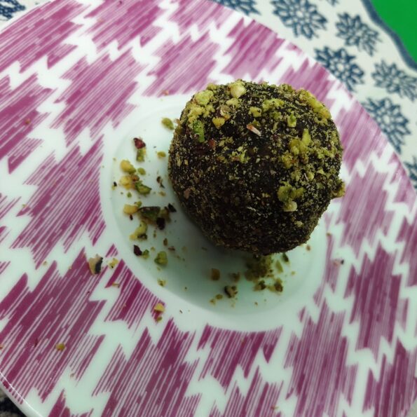 A dish with a chocolate pistacchio truffle