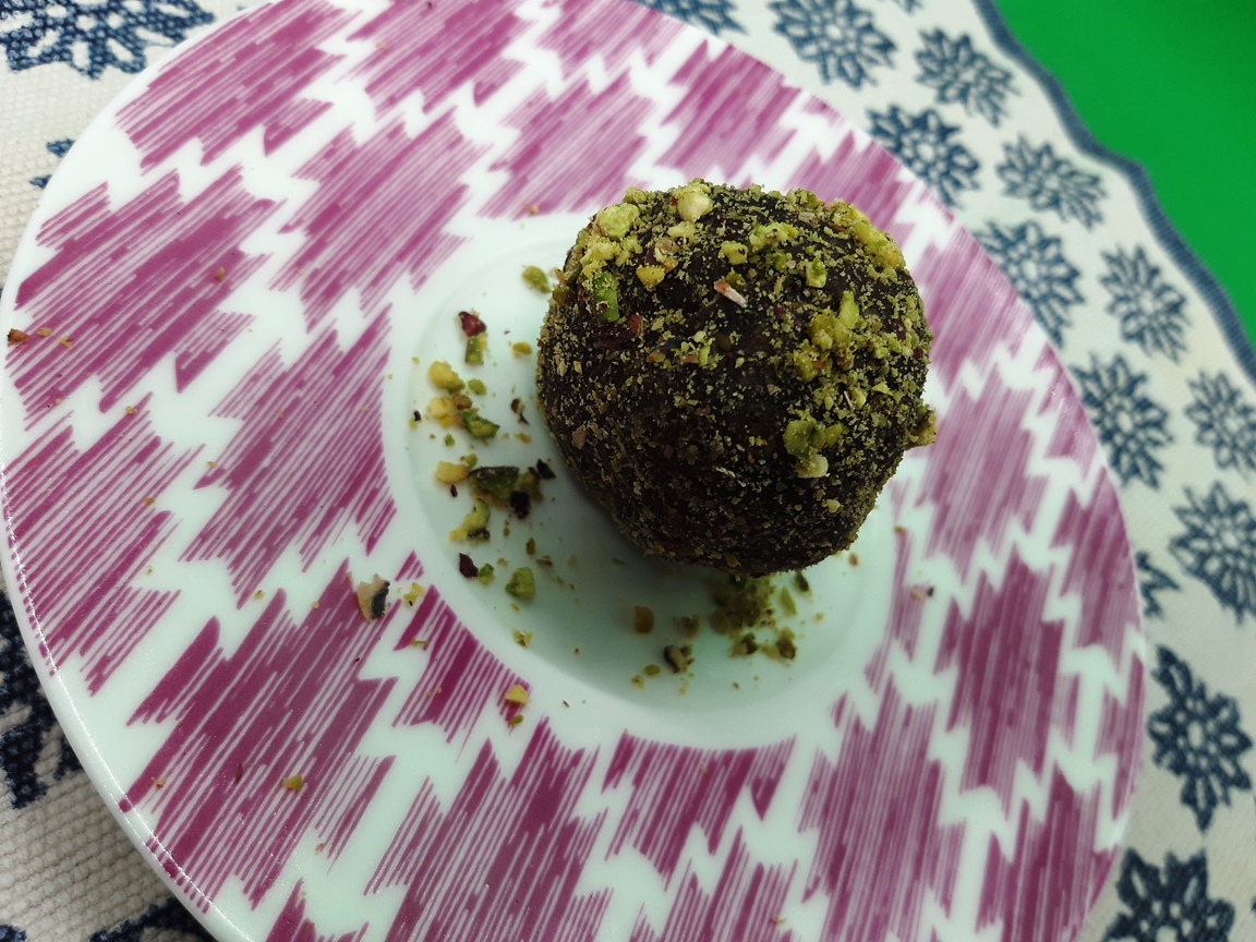 A dish with a chocolate pistacchio truffle