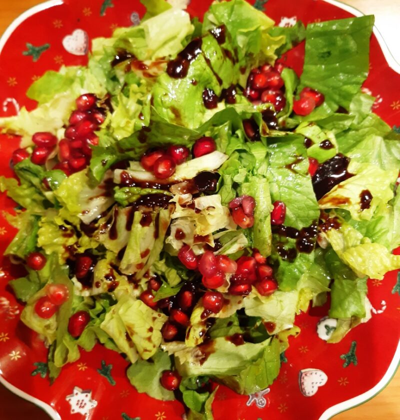 A red salad bowl with christmas decoration with a lettuce salad