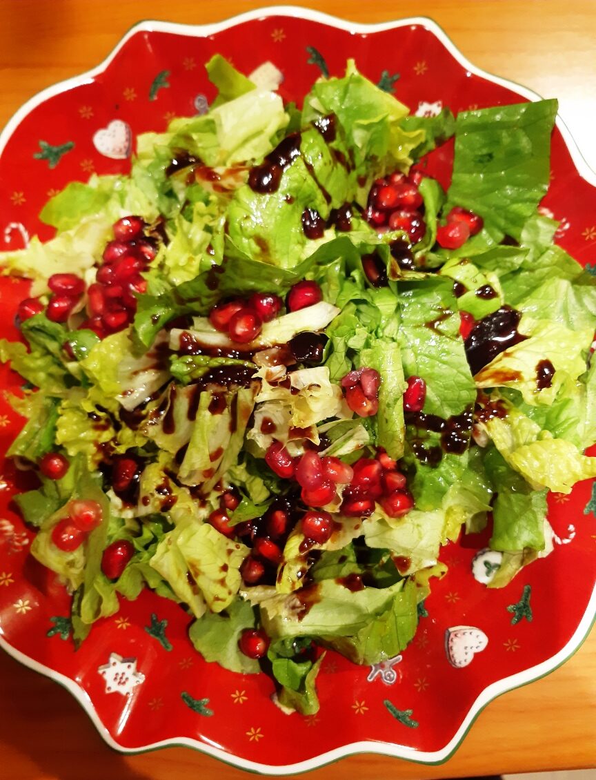 A red salad bowl with christmas decoration with a lettuce salad