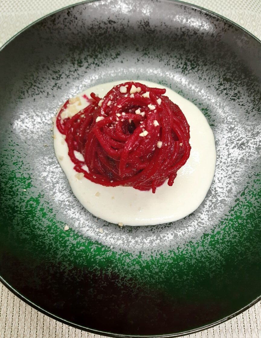 black dish with red spaghett and white creamy sauce