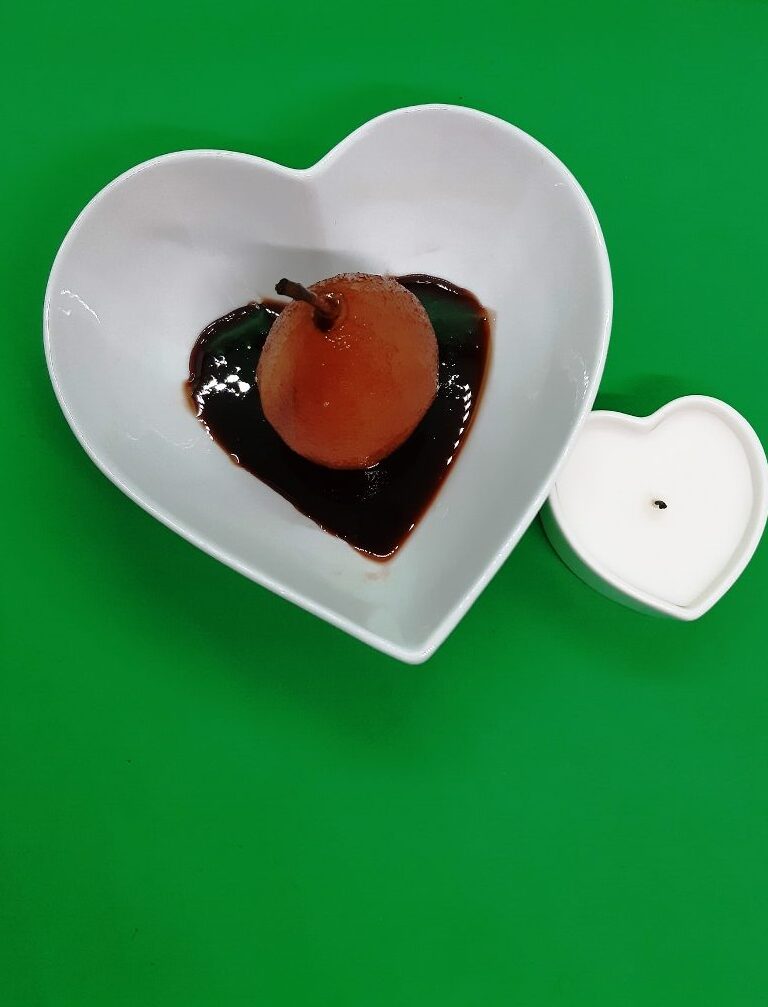 Red pear in red sauce in a heart shaped dish