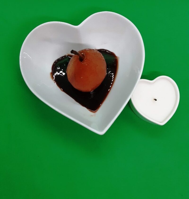 Red pear in red sauce in a heart shaped dish