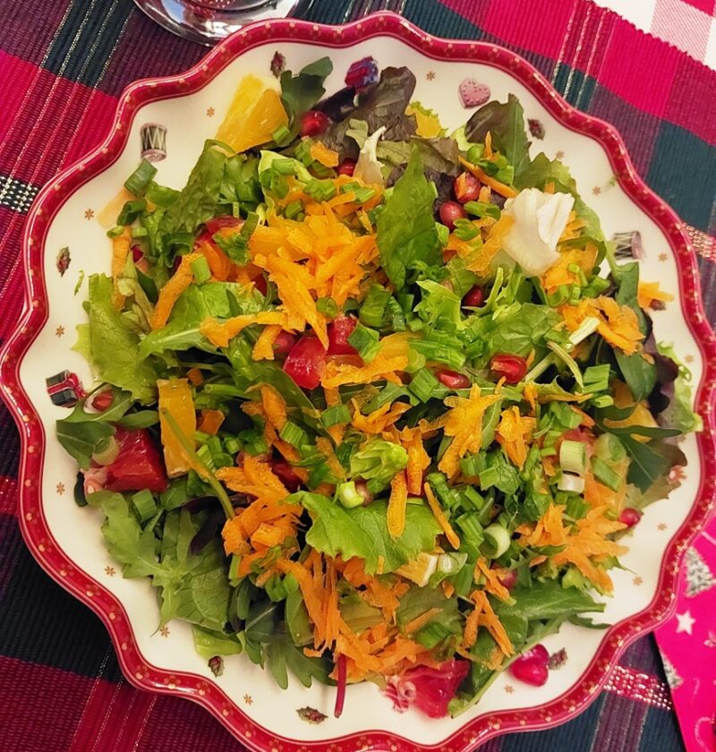 A salad with greens, carrot in a festive dish
