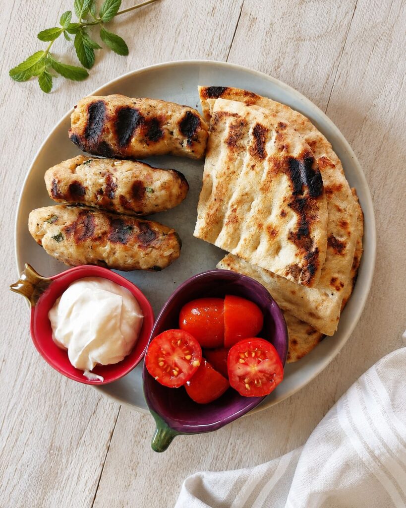 Juicy grilled chicken kebabs served with creamy Greek yogurt sauce, warm pita bread and fresh tomatoes.